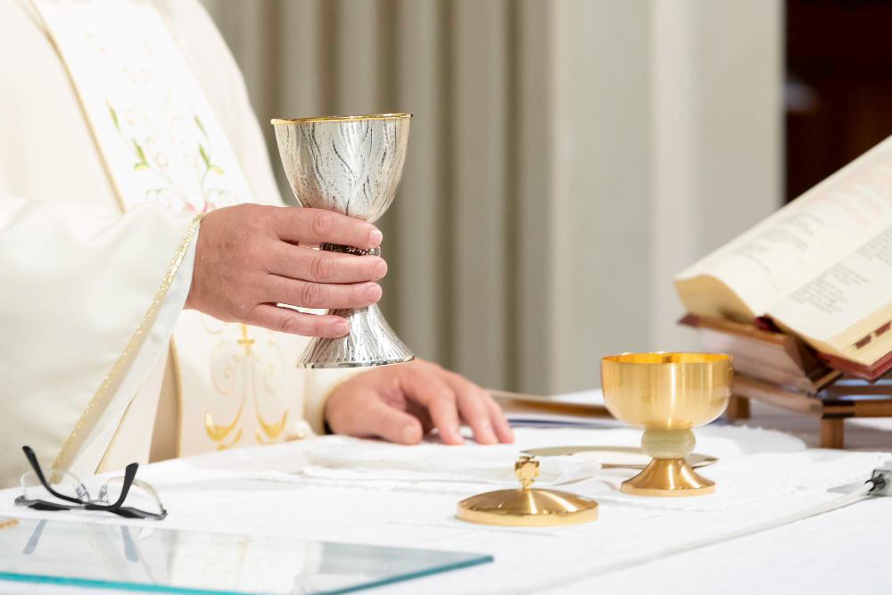 Sacerdote che solleva la coppa col vino durante la funzione